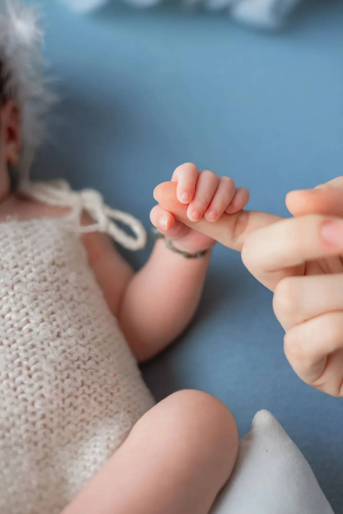 Een babyhandje houdt een vinger vast